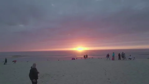 Wide drone advancing toward sunset with people on Dune du Pilat, France Stockbeeldmateriaal 333107901