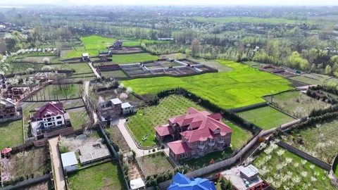 Wide drone orbit over a rural Kashmir settlement and spring farmlands. Stock-Footage 333800899