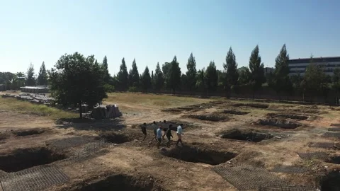Wide Drone Perspective of Laborers Walking Through Foundation Pits at Видео 339095494