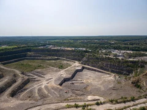 Wide drone shot captures massive terraced stone quarry with dirt tracks, exca Fotos Stock