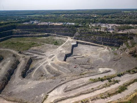 Wide drone shot captures massive industrial stone quarry with rocky terraces, Photos