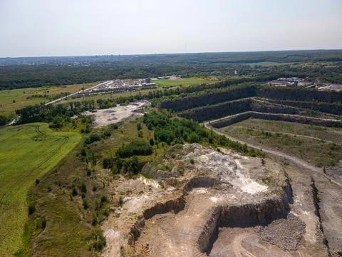 Wide drone shot captures massive terraced stone quarry with dirt tracks, exca Fotos Stock