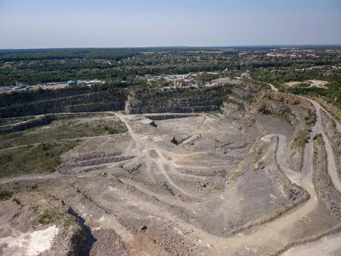 Wide drone shot captures massive terraced industrial quarry with winding dirt Fotos Stock