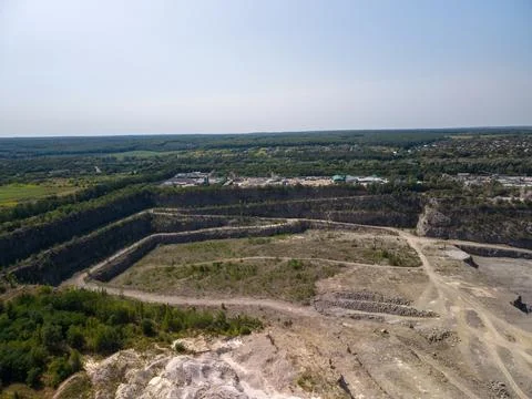 Wide drone shot captures massive terraced stone quarry with dirt tracks, exca Fotos Stock