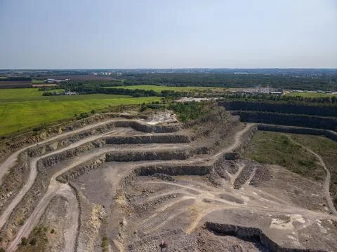 Wide drone shot captures massive terraced stone quarry with winding dirt trac Fotos Stock