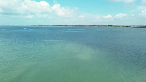Wide drone shot following multiple jetskis racing parallel to the shore, their Stock Footage 321355305