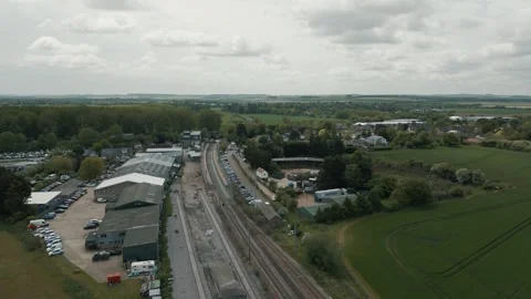 Wide drone shot moving backwards train tracks and a train station Stock Footage 296803112