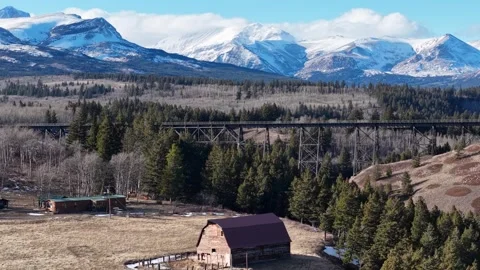 Wide drone shot over a rustic barn and homestead on an open field surrounded by Stock Footage 332559551