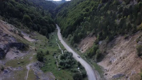 A wide Drone shot tracking a Car Driving a Road moving through the wilderness Stock Footage 194554444