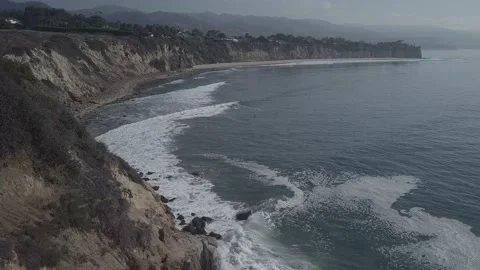 Wide drone shot of waves at the beach with surfers floating in the water Stock Footage 167553448