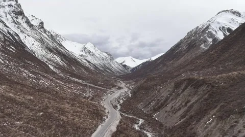 Wide drone view of mountain road crossing rugged terrain in China Stock Footage 337900297