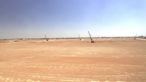 Wide drone view of sandy ground and distant construction cranes 库存影片 346428644