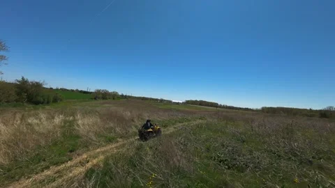 Wide drone view tracking people riding a yellow ATV down a dirt path Video stock 341756188