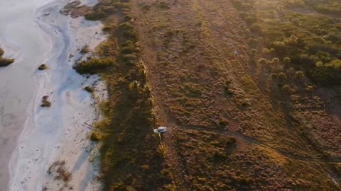 Wide dynamic drone shot of white overland vehicle parked on the shore of a 스톡 동영상 231454162