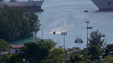 Wide elevated shot: small boat cruising in a bay or port. HD50p Stock Footage 244394662