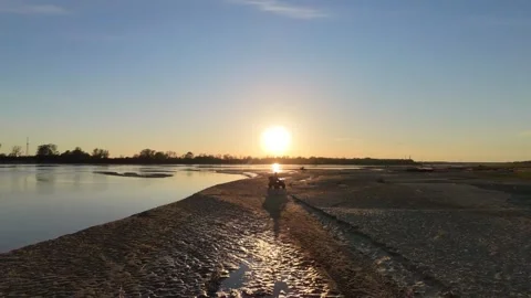 Wide epic drone shot of atv driving on a beach during sunset Stock Footage 334199917