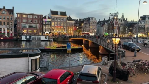 A wide evening shot captures a yellow canal boat gliding under a glowing bridge Stock-Footage 334009812