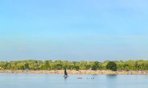 A wide expanse of sandy beach teeming with sunbathers and swimmers, backed by Stock Photos