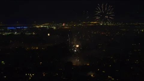 Wide flyover view of fireworks exploding in sky over cityscape at night / 動画素材 94436930