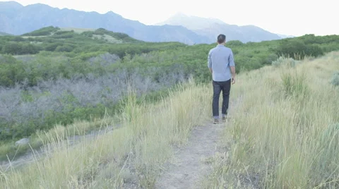 Wide Handheld of Man Walking Down Path Touching Weeds with Hand 動画素材 68723671