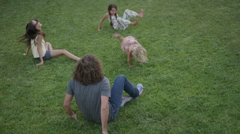 Wide high angle shot of father and daughters rolling on lawn / Orem, Utah, Stock Footage 68220012