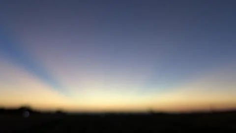 A wide horizontal shot captures blurred crepuscular sun rays radiating from.. Stock Photos