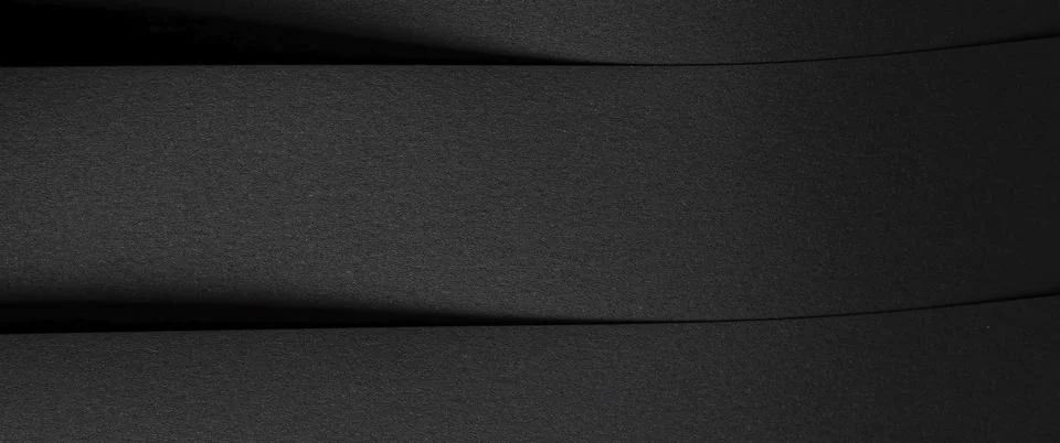 Wide horizontal view of layered dark paper sheets forming soft curved lines a Stock Photos