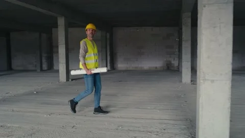 Wide image of caucasian engineer walking on construction site and holding projec Stock-Footage 165044547