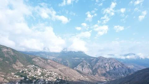 Wide Iranian mountain range under a blue sky with clouds, a hillside town Stock Photos
