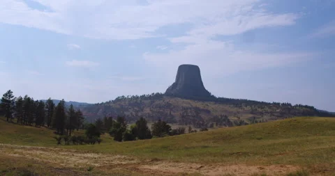 Wide Landscape of Devils Tower Across Meadow and Pine Trees Stock Footage 340245046