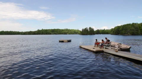 Wide Landscape Including Lake, Trees and People Relaxing on A Dock Stock Footage 66564841