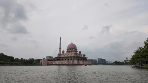 Wide landscape view of the pink Putra Mosque sitting on Putrajaya Lake Stock Footage 340875320