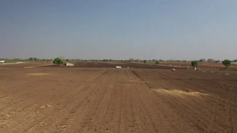 Wide low-angle aerial shot overlooking a vast dry brown agricultural field Stock Footage 336883202