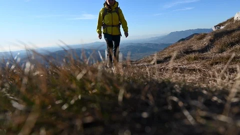 Wide low angle locked down shot of a female hiker walking up the mountain path Stock Footage 124617657