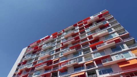 Wide low angle shot of modern apartment tower revealed from behind tree branches Stock Footage 340273677
