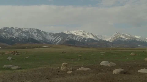 Wide mountain landscape with snow capped peaks and grassy valley panorama Vidéo 333953199