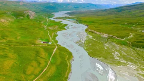 Wide Mountain River Flowing Through a Green Alpine Meadow Stock-Footage 341645781