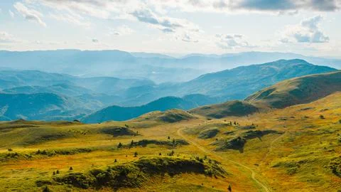 Wide mountain view with sun rays spreading through clouds and valleys Stock Photos