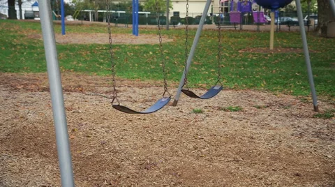 A wide moving shot of empty swings moving in a park. Stock Footage 56657708