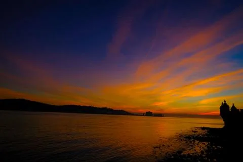 Wide multicolored sunset over river water reflections and Belem tower Stock Photos