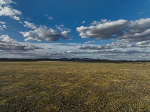 A wide open grassy plain extends toward a faint mountain range under sky Stock Photos