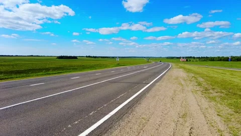 Wide open road with green fields and blue sky in rural area 스톡 동영상 339467702