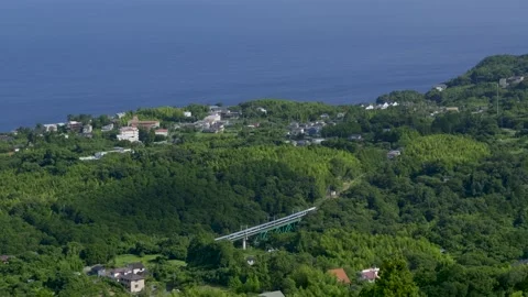 Wide open view of Odoriko train passing through Izu countryside with ocean Stock Footage 345155890