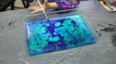 Wide paintbrush with blue paint for sprinkle over water for marble patterns Stock Footage 42050708