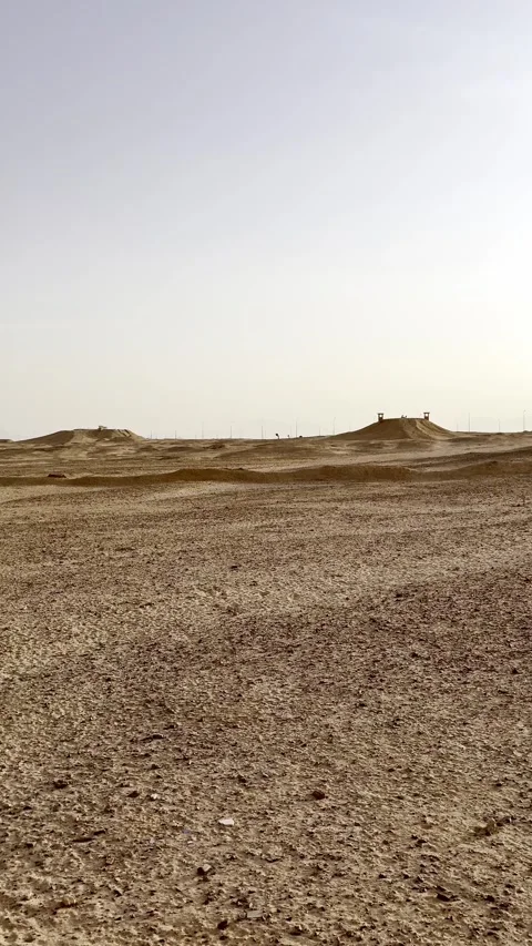 Wide pan across dry desert terrain under a bright hazy sky Stock Footage 345744597