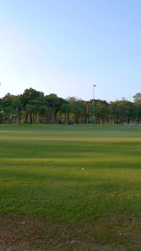 Wide Pan of Lush Green Golf Course Fairway and Putting Green Stock Footage 337994896