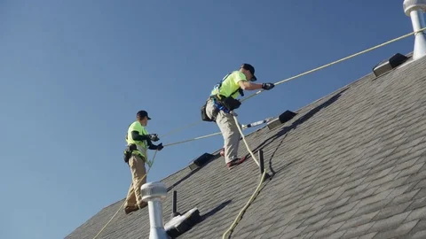 Wide panning low angle shot of workers on roof checking safety lines / Mapleton, Stock Footage 77469014