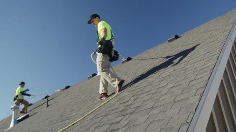Wide panning low angle shot of workers on roof checking safety lines / Mapleton, Stock Footage 77469056