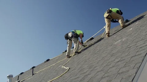 Wide panning low angle shot of workers drilling on roof / Mapleton, Utah, United Stock Footage 77469098