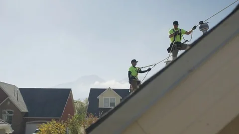 Wide panning low angle shot of workers drilling on roof / Mapleton, Utah, United Stock Footage 77469121